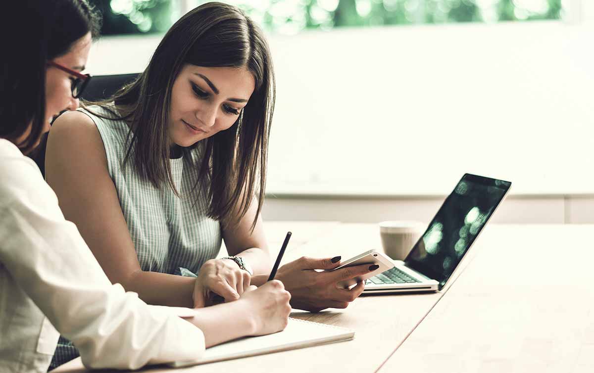 Zwei Frauen sitzen vor einem Laptop