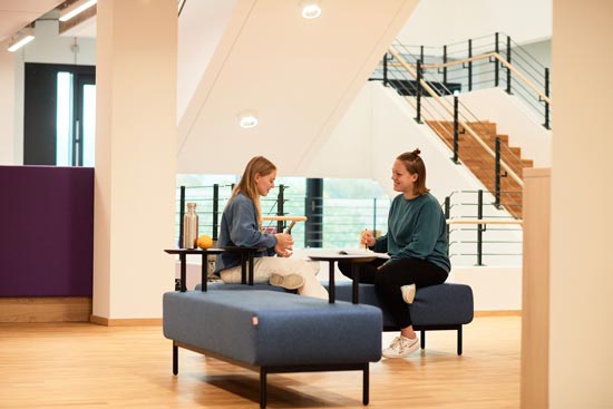 Studierende auf Sitzbänken im Treppenhaus der EH Freiburg