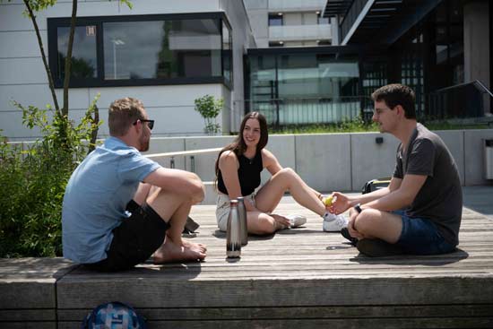 3 Studierende bei der Pause auf dem Campus