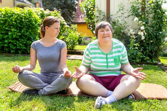 ältere Dame und junge Frau machen gemeinsam Yoga
