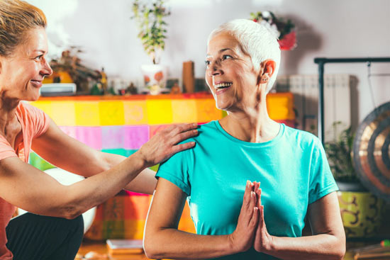 ältere Dame und junge Frau machen gemeinsam Yoga