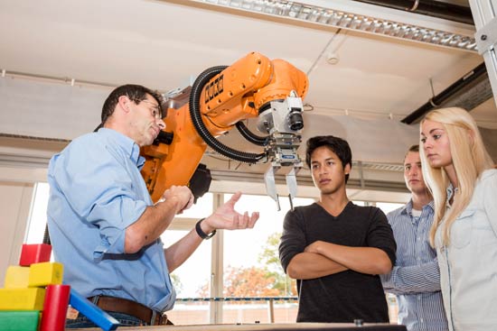 Studierende stehen mit Dozent an einer Maschine