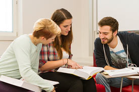 Studierende sitzen mit Ordnern und Büchern zusammen