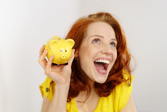 Glückliche Frau mit einem gelben Sparschwein