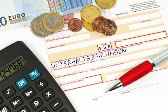 Überweisungsträger mit Betreff „Unterhaltszahlung“, daneben Geld und ein Taschenrechner