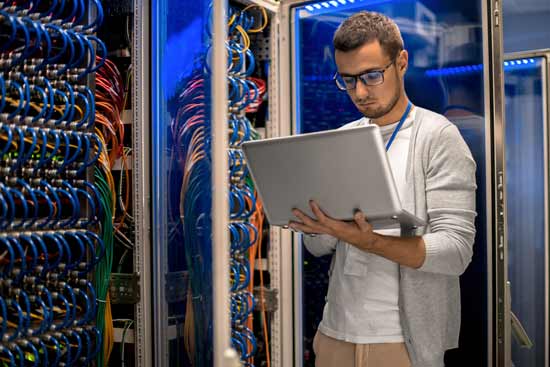 Mann mit Laptop im Serverraum