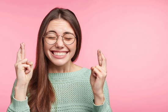 Studentin mit geschlossenen Augen kreuzt die Finger