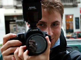 Lächelnder Fotograf hält seine Kamera ins Bild
