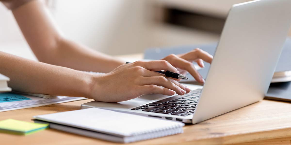 Hände einer jungen Frau tippen auf der Tastatur eines Laptops