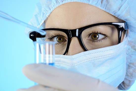 Biomedizinerin schaut Inhalt eines Reagenzglases an