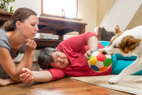 Geistig behinderte Frau spielt betreut mit einem Hund