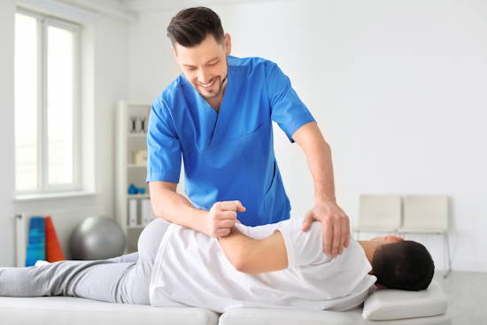 Ein Physiotherapeut arbeitet mit einem Patienten in einer Praxis