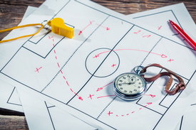 Fusball-Taktikschema, darauf liegend Pfeife und Stoppuhr