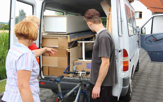 Student mit Mutter an an der Rücktur eines Transporters, Fahrrad in der Hand