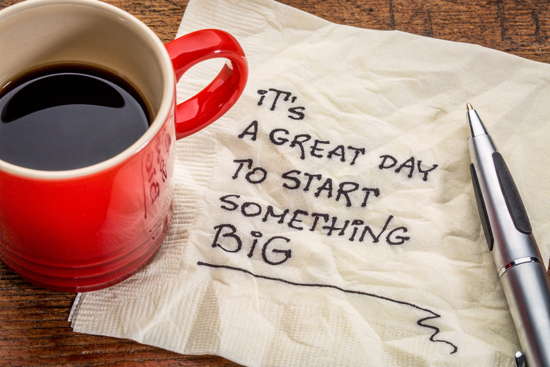 Tasse Kaffe, Kugelschreiber und Serviette, auf der „It's a great day to start something BIG“ geschrieben wurde
