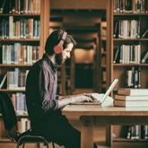 Student mit Laptop in altehrwürdiger Bibliothek