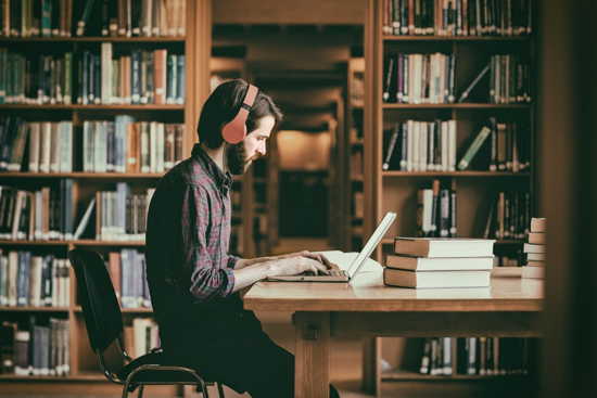 Student mit Laptop in altehrwürdiger Bibliothek