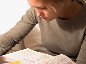 Studentin schaut in dickes Buch, in dem viele Zeilen markiert sind.
