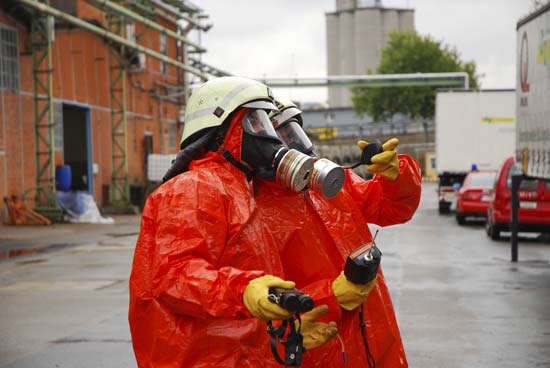 Zwei Menschen in Schutzausrüstung mit Helm, Handschuhen und Atemmaske
