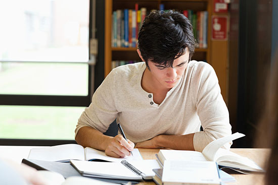 Student sitzt in der Bibliothek an einer Hausarbeit