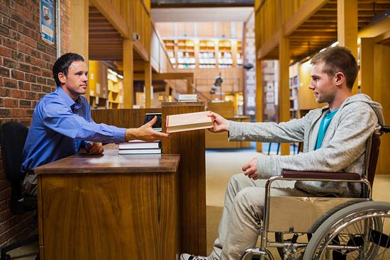 Student im Rollstuhl an der Bücherrückgabe der Bibliothek