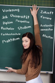 Studentin steht an Tafel, auf der verschiedene Begriffe rund ums Studium stehen.
