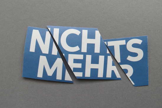 Schriftzug NICHTS MEHR auf blauem, in drei Teile zerschnittenem Bogen auf grauem Hintergrund